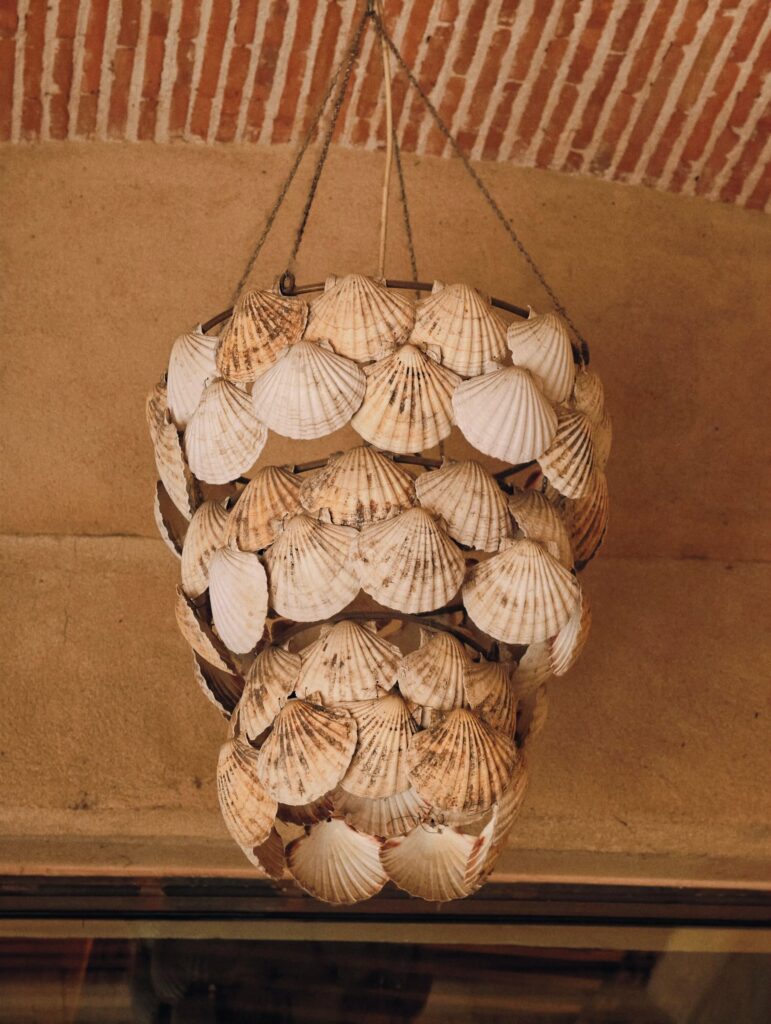 Lámpara colgante hecha de conchas de vieira bajo una bóveda de ladrillo