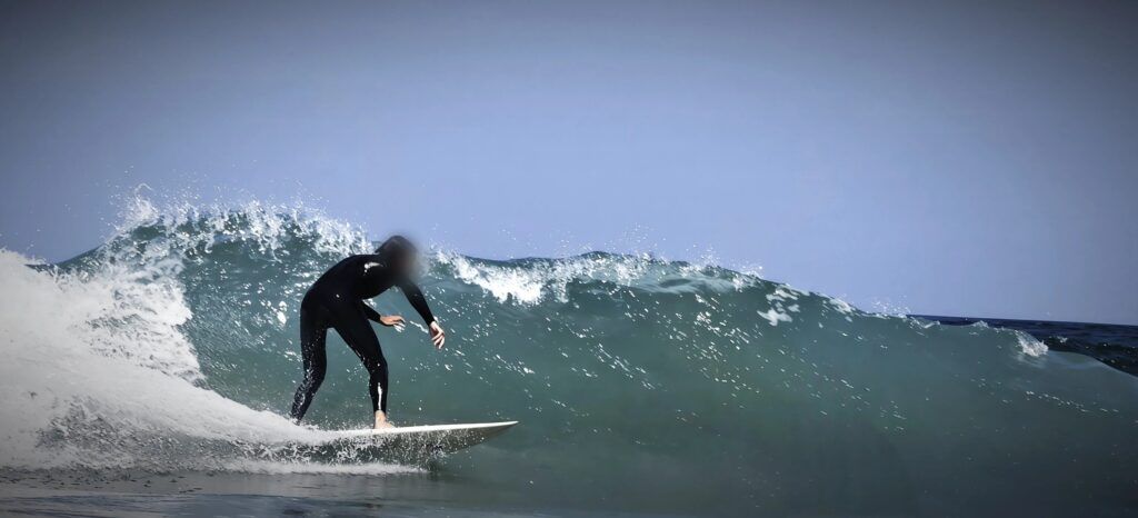 Surfista recorriendo una pared de agua verde con la cresta rompiendo detrás de él